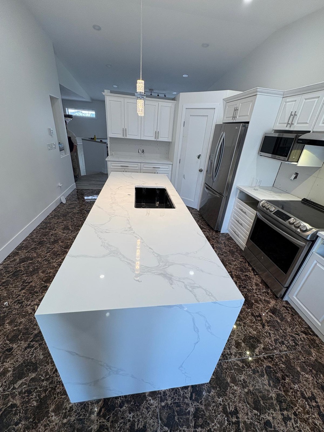 Calacatta quartz island with undermount sink in a white Calgary kitchen