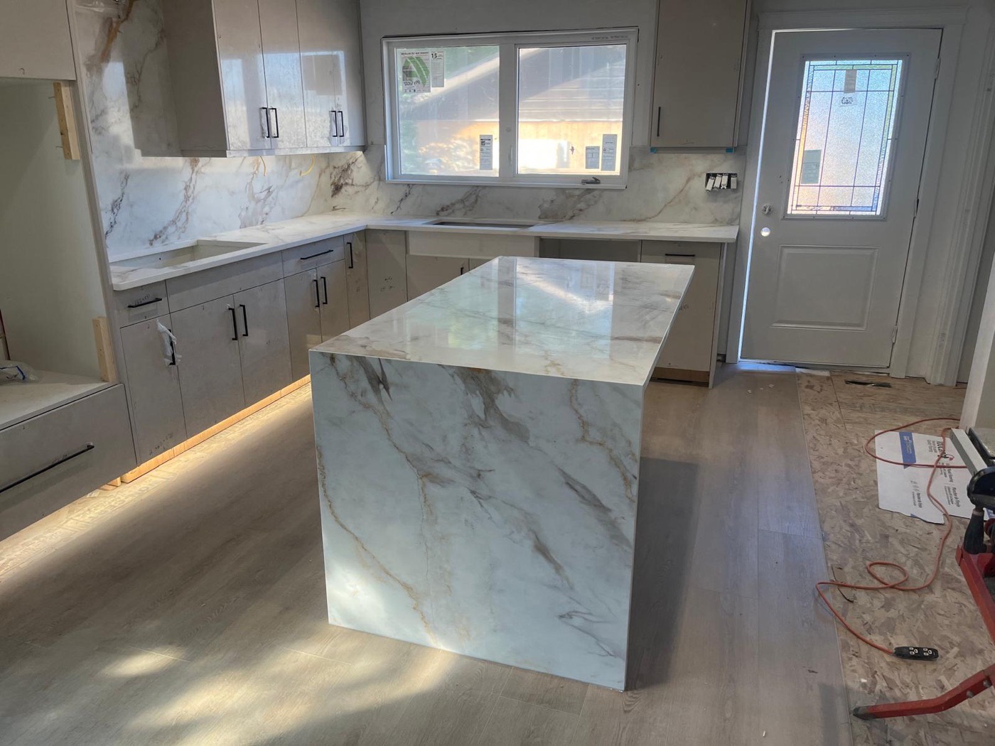 Marble-look waterfall island, matching backsplash, Calgary install by Bedrock Countertops