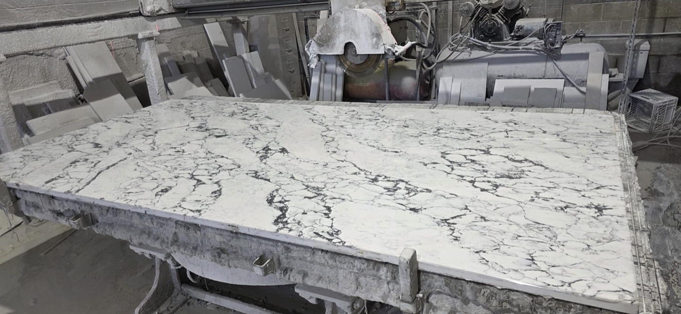 Stone slab being cut on a bridge saw inside Bedrock Countertops' Calgary fabrication shop